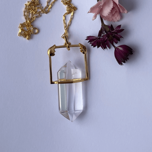 A beautiful clear crystal minimalist pendant mounted in gold vermeil with little gold angel wings on the setting